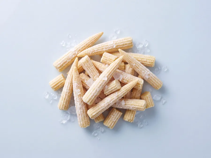 Frozen baby corn spears, whole and cut, dusted with frost